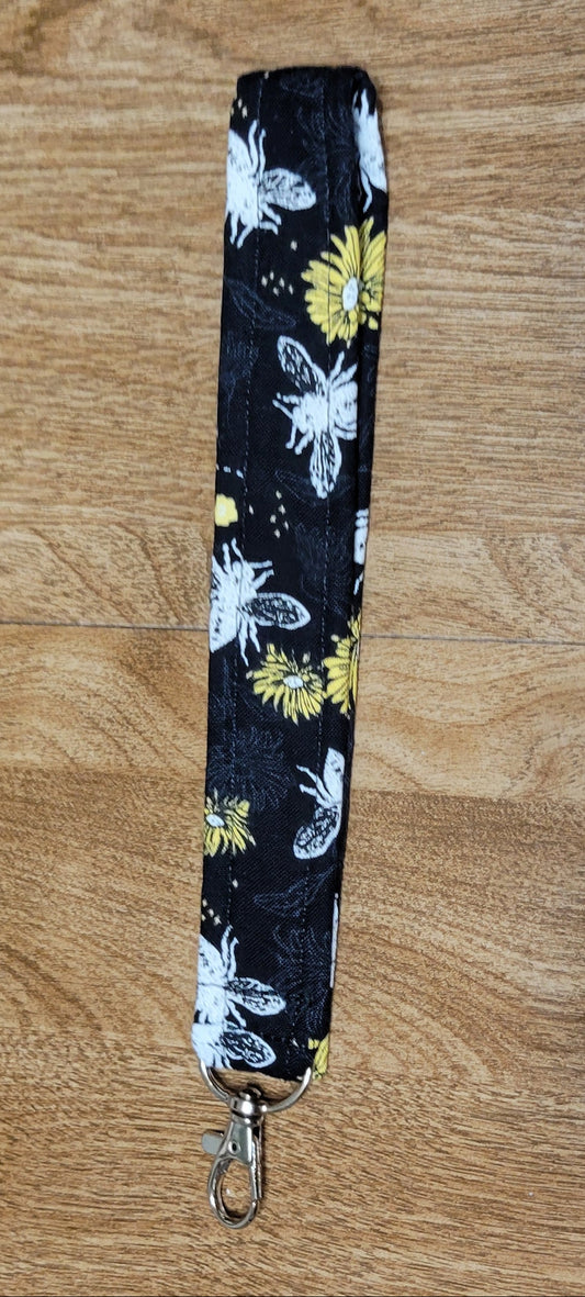 White bee and Floral-patterned lanyard on a wooden surface