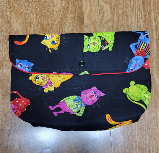 Make up bag with a colorful cats with with a black background, red solid inside with a snap.