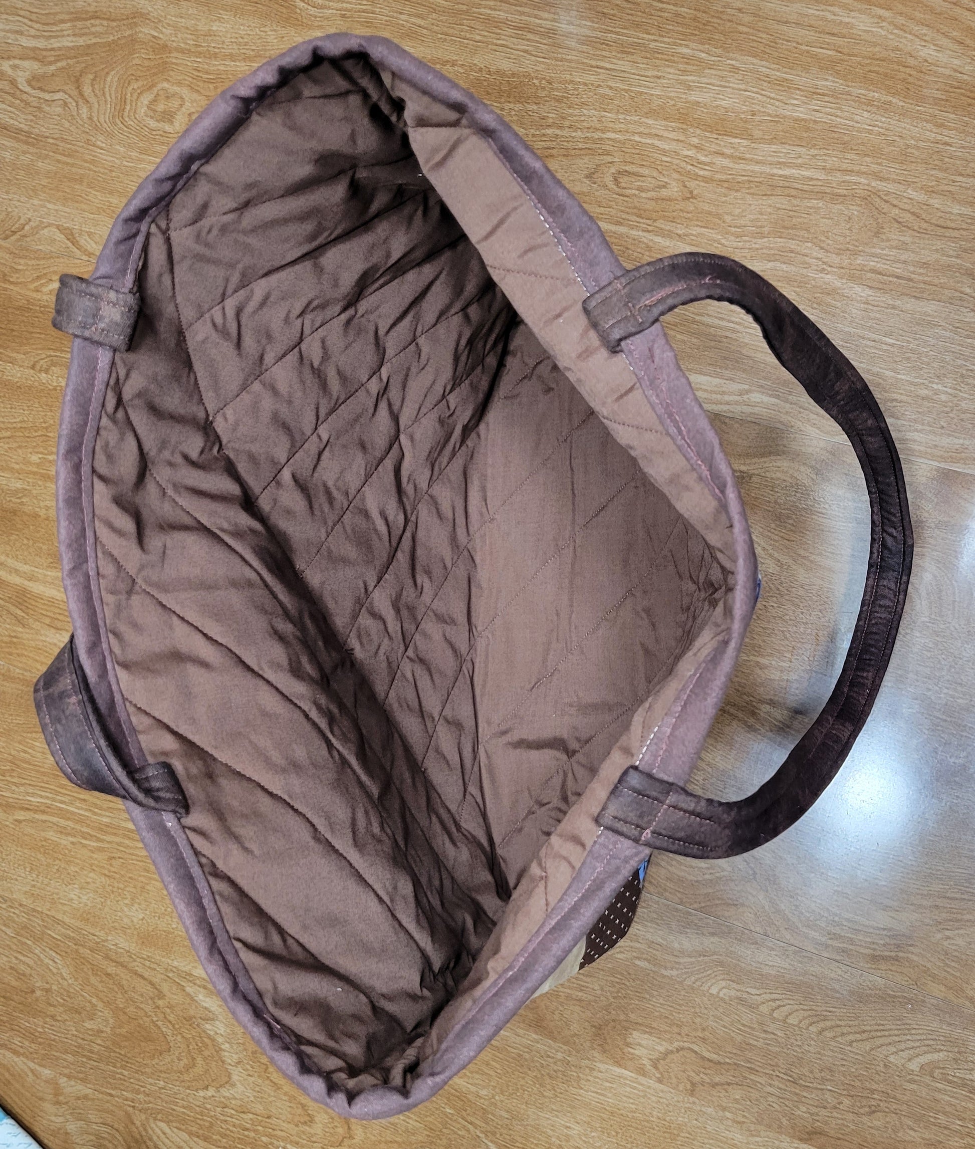 Brown quilted bag on a wooden surface with colorful items around