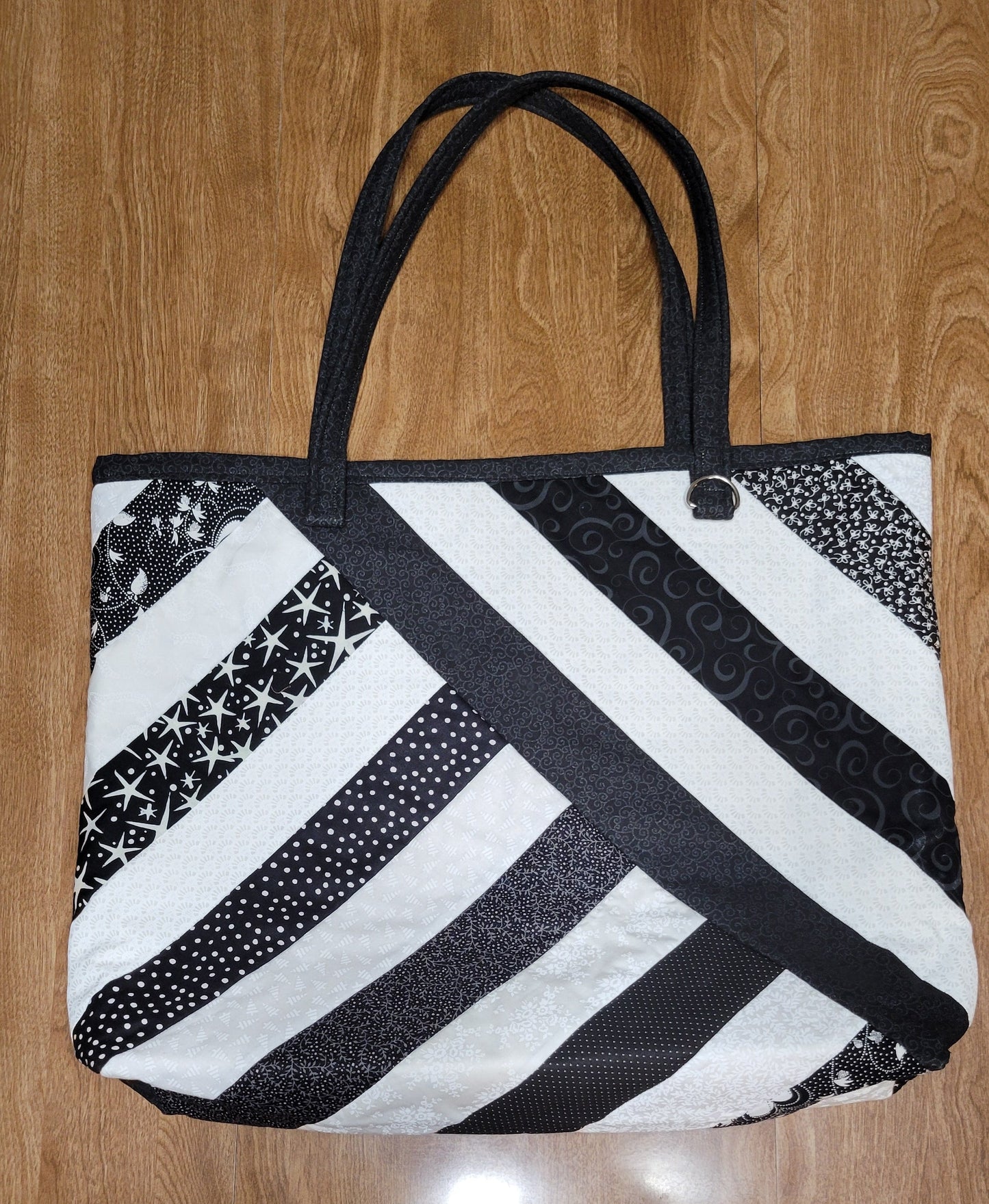 Black and white patterned tote bag on a wooden floor
