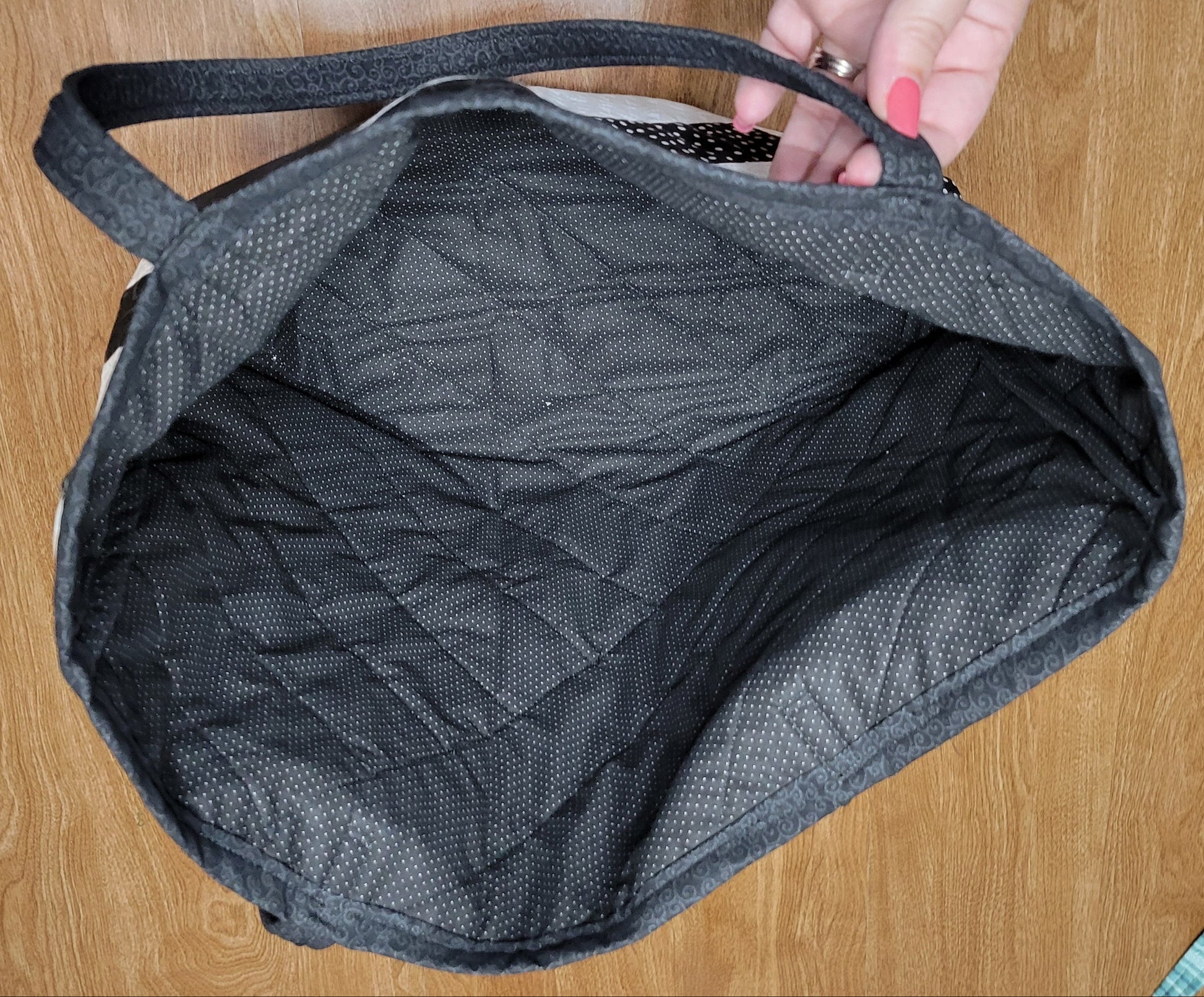 Gray bag on a wooden surface with a hand holding it