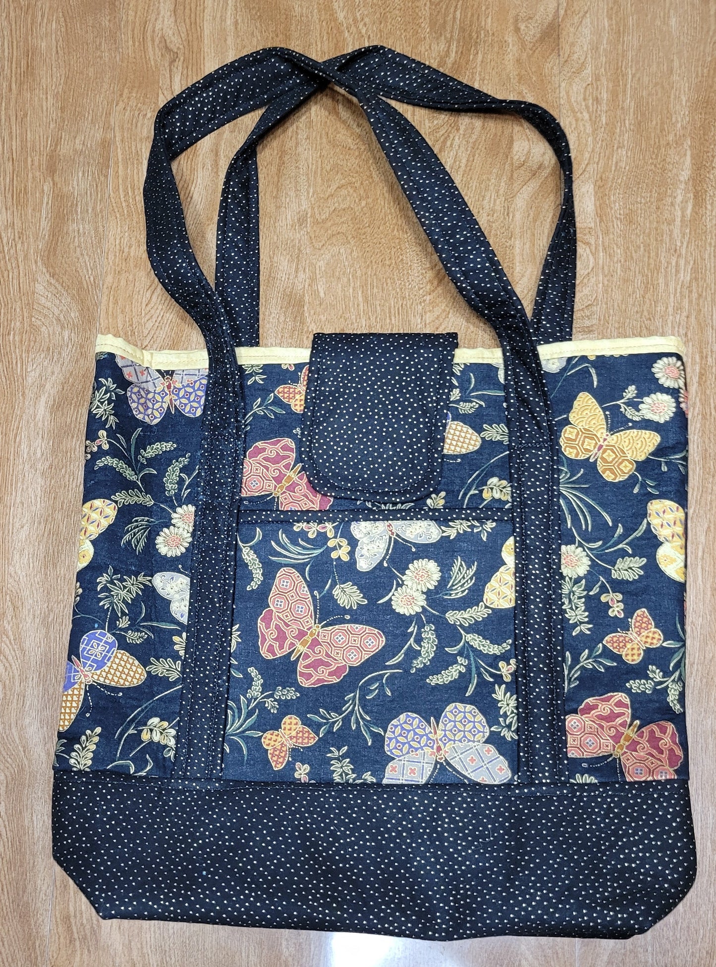 Butterfly Floral-patterned bag with a black strap on a wooden surface