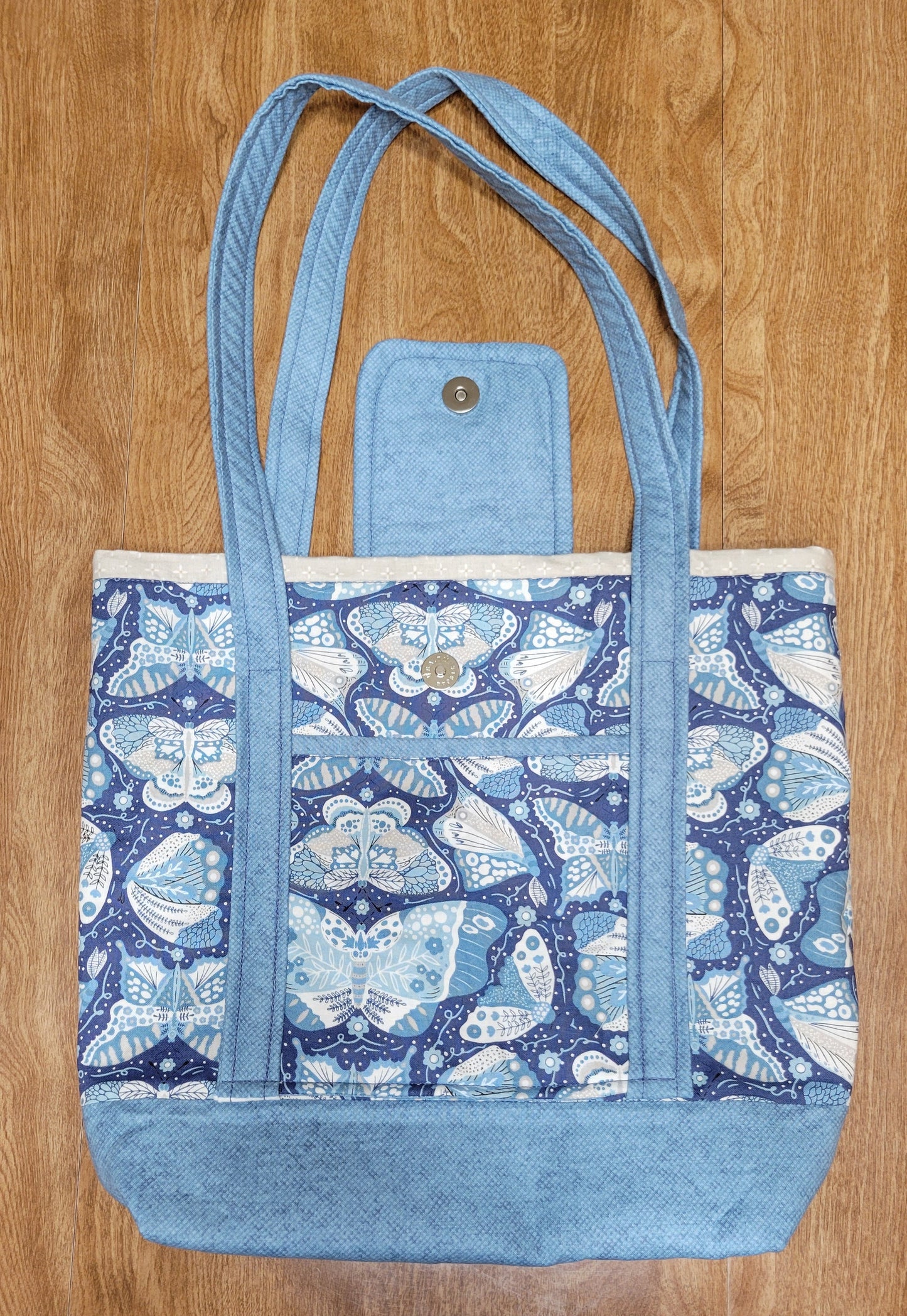Blue Butterfly-patterned bag with a matching strap on a wooden surface
