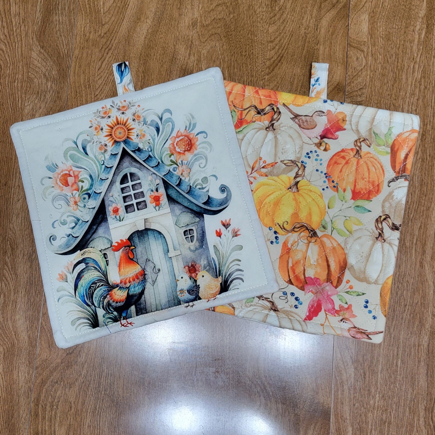 Two decorative pot holders with autumn-themed designs on a wooden surface.