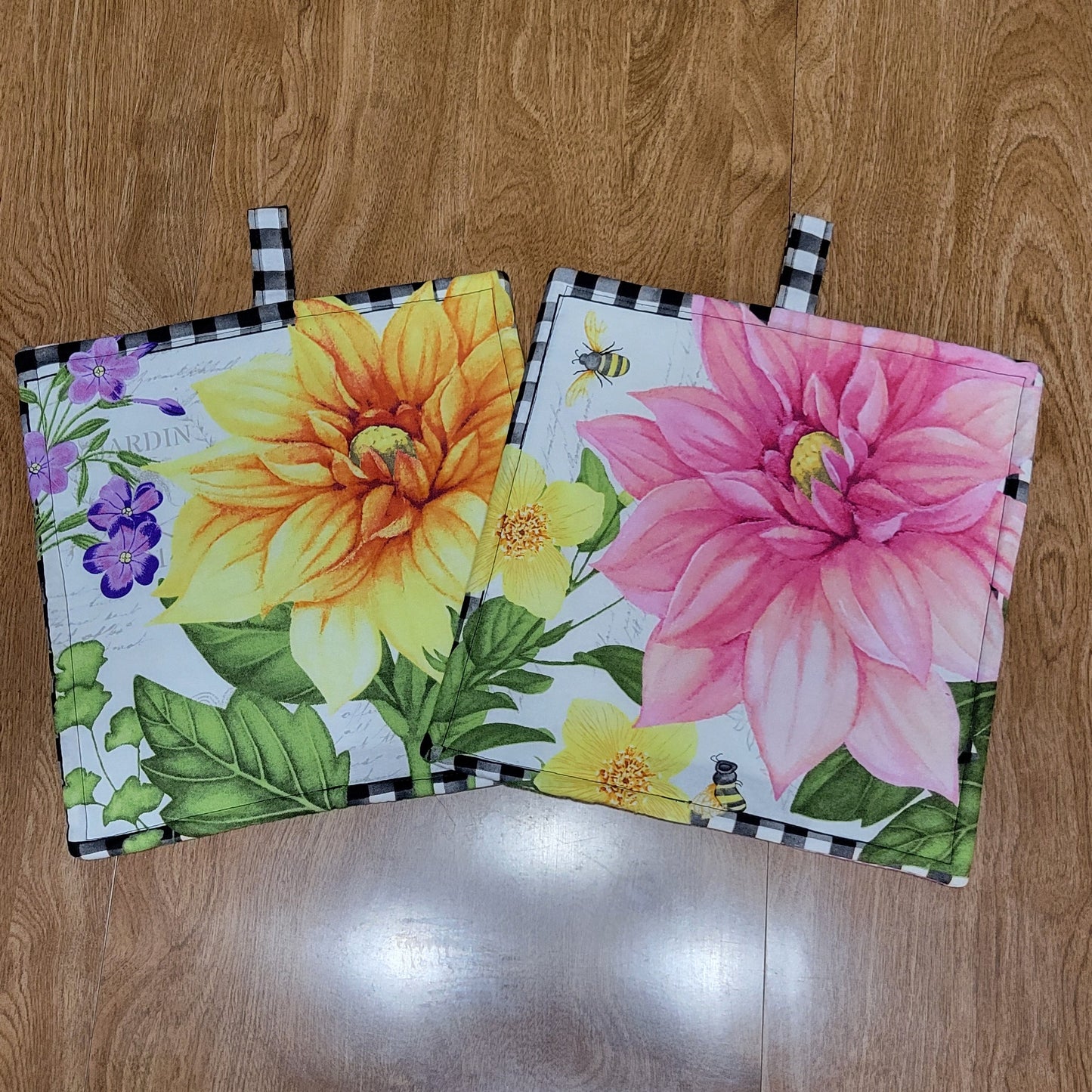Two floral bright pot holders on a wooden surface