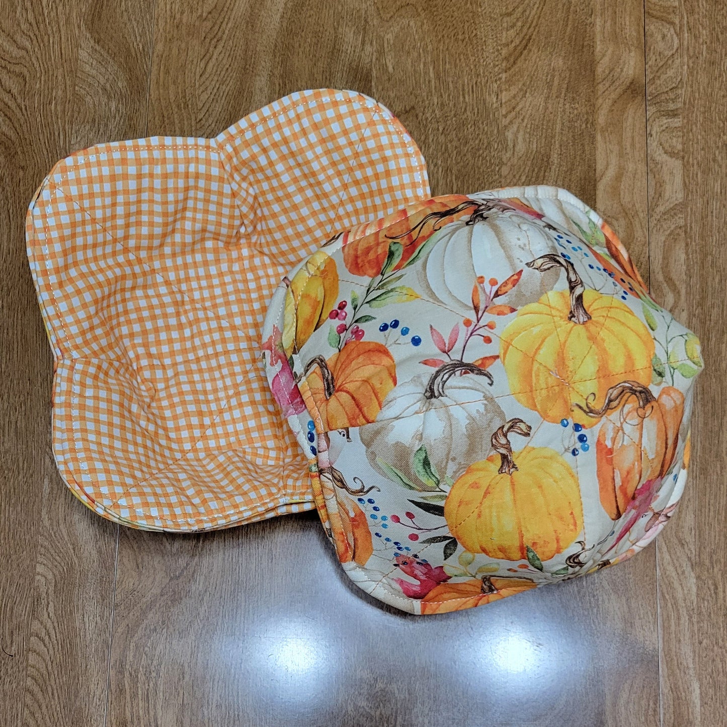 Pumkin - patterned fabric and a checkered orange and white fabric on a wooden surface.