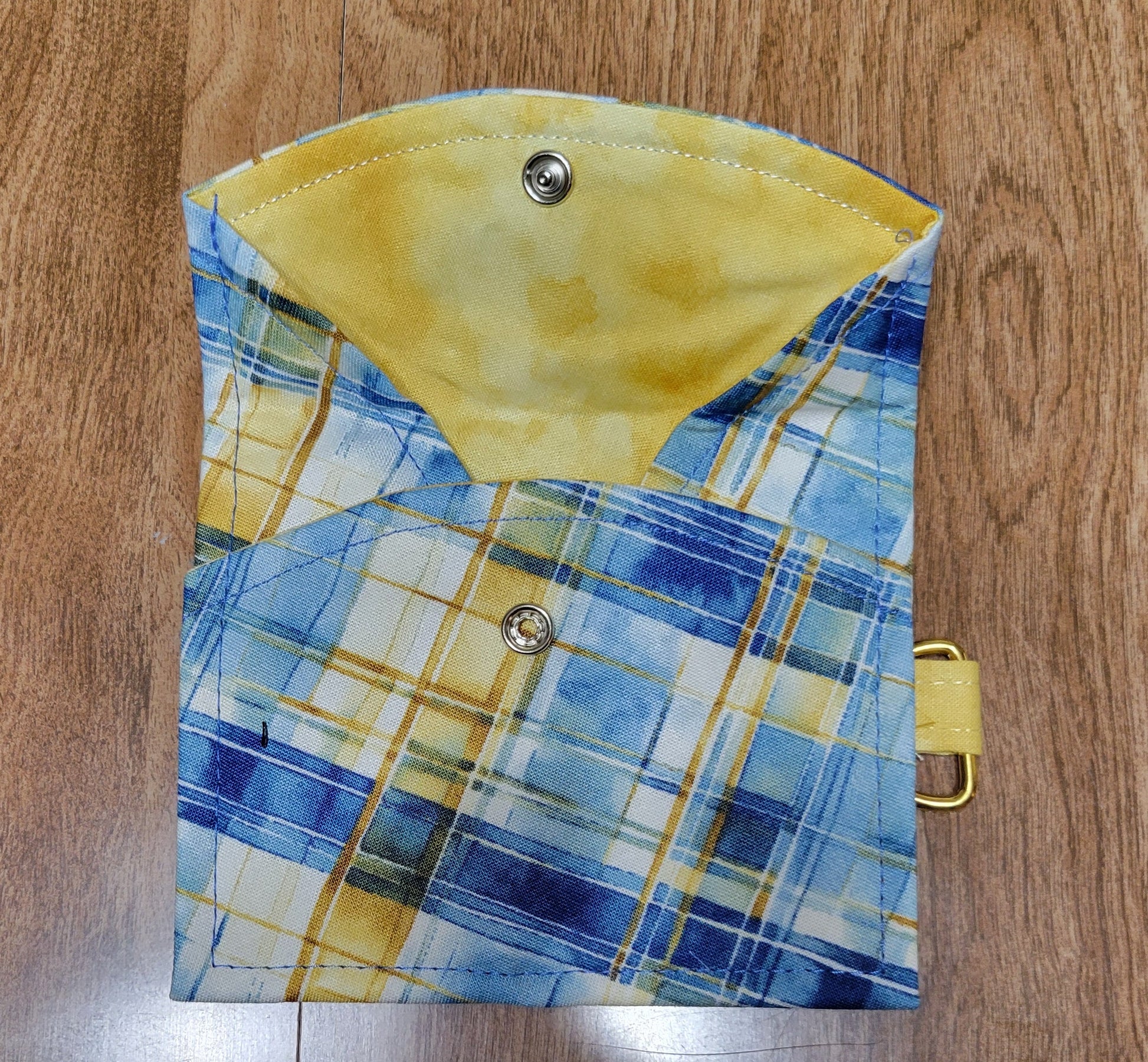 Plaid pouch with yellow accents on a wooden surface