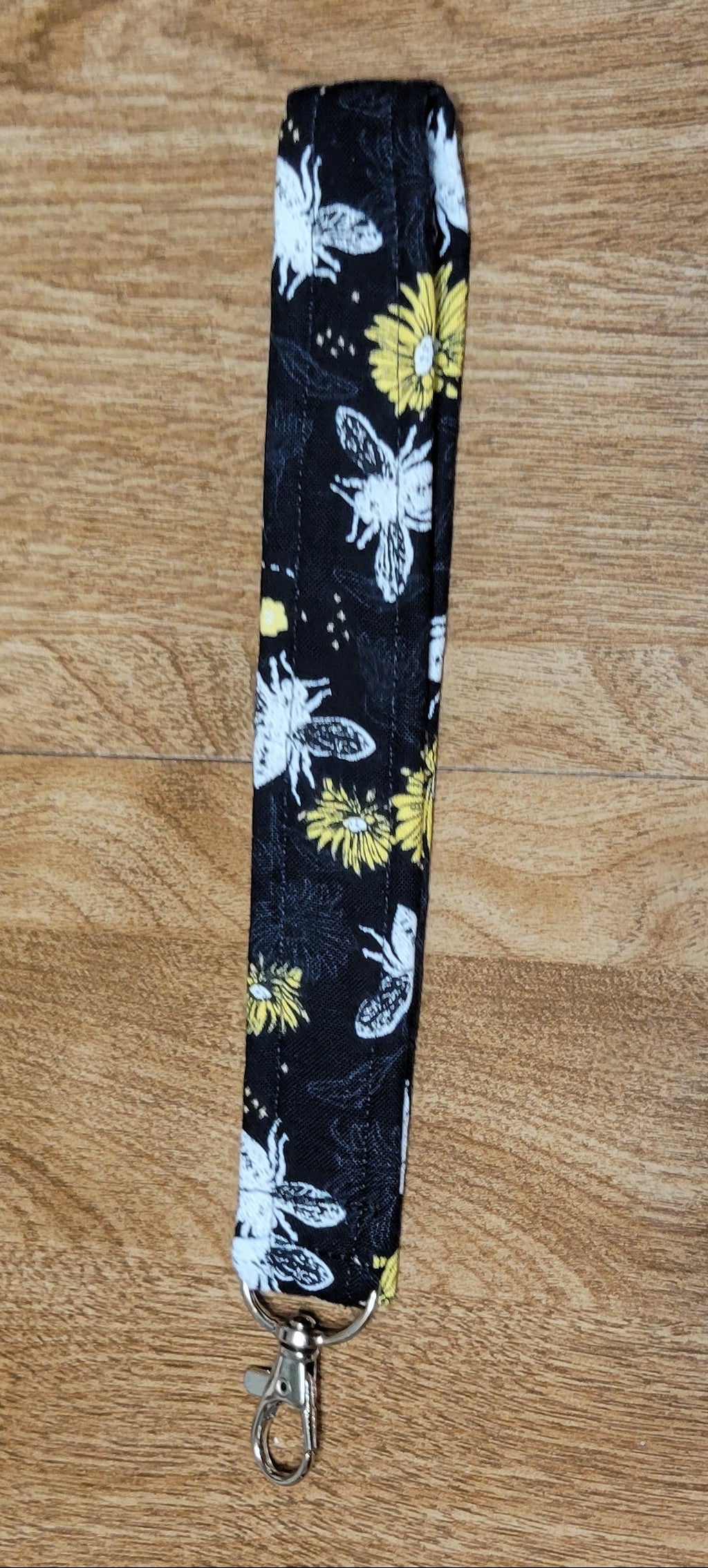 White bee and Floral-patterned lanyard on a wooden surface