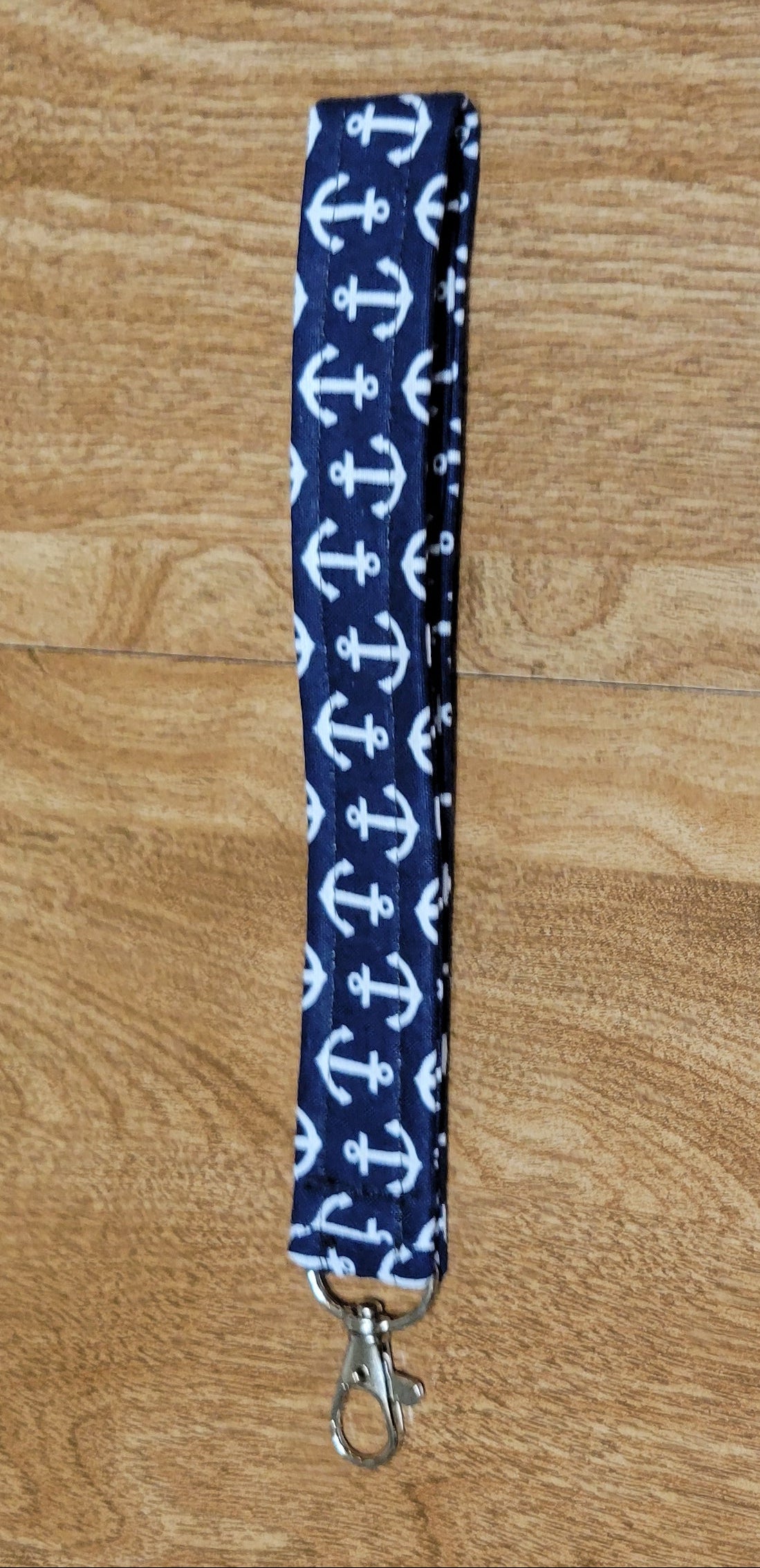 Blue lanyard with white anchor pattern on a wooden surface