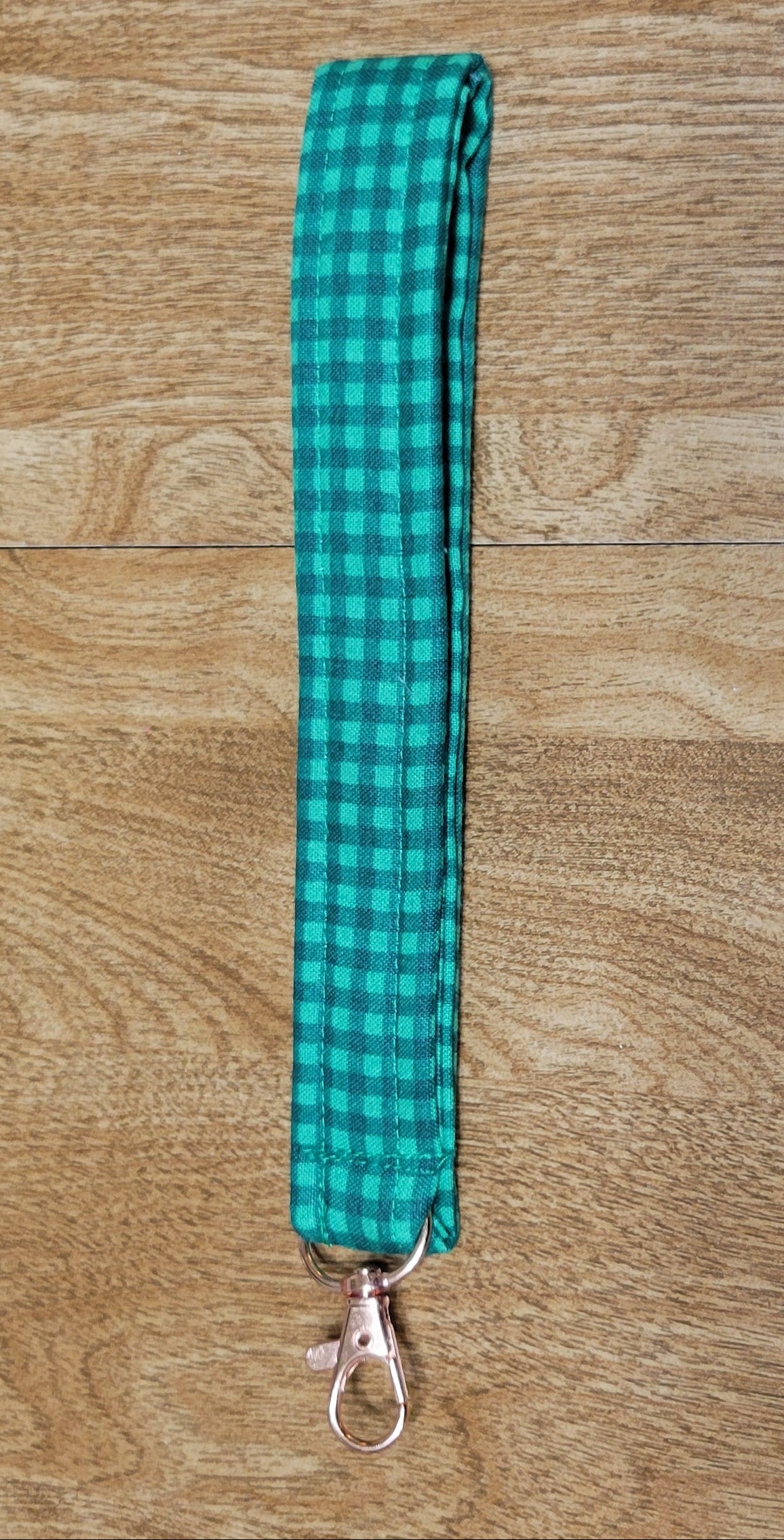 Green checkered lanyard on a wooden surface