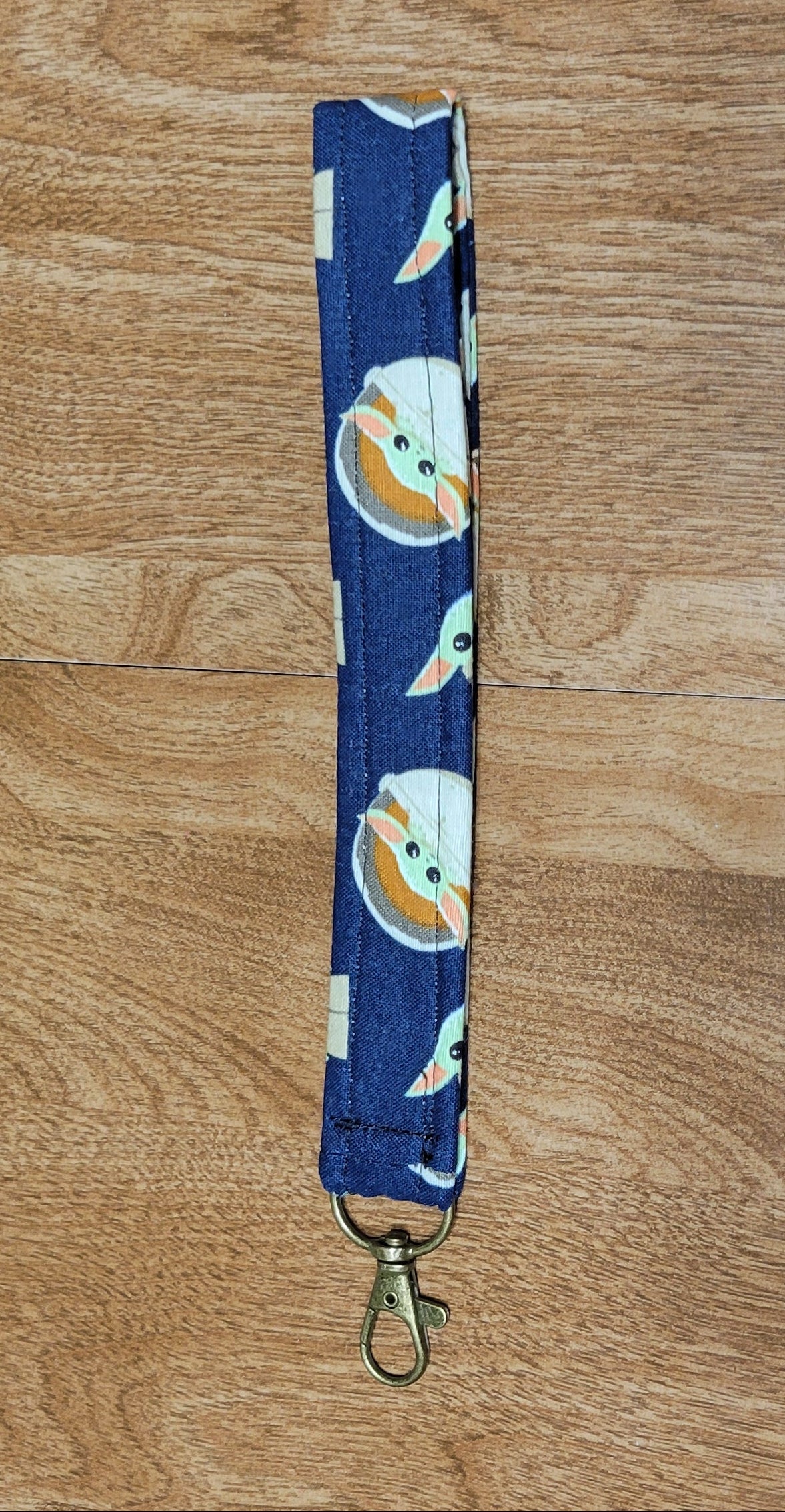 Blue lanyard with cartoon character design on a wooden surface