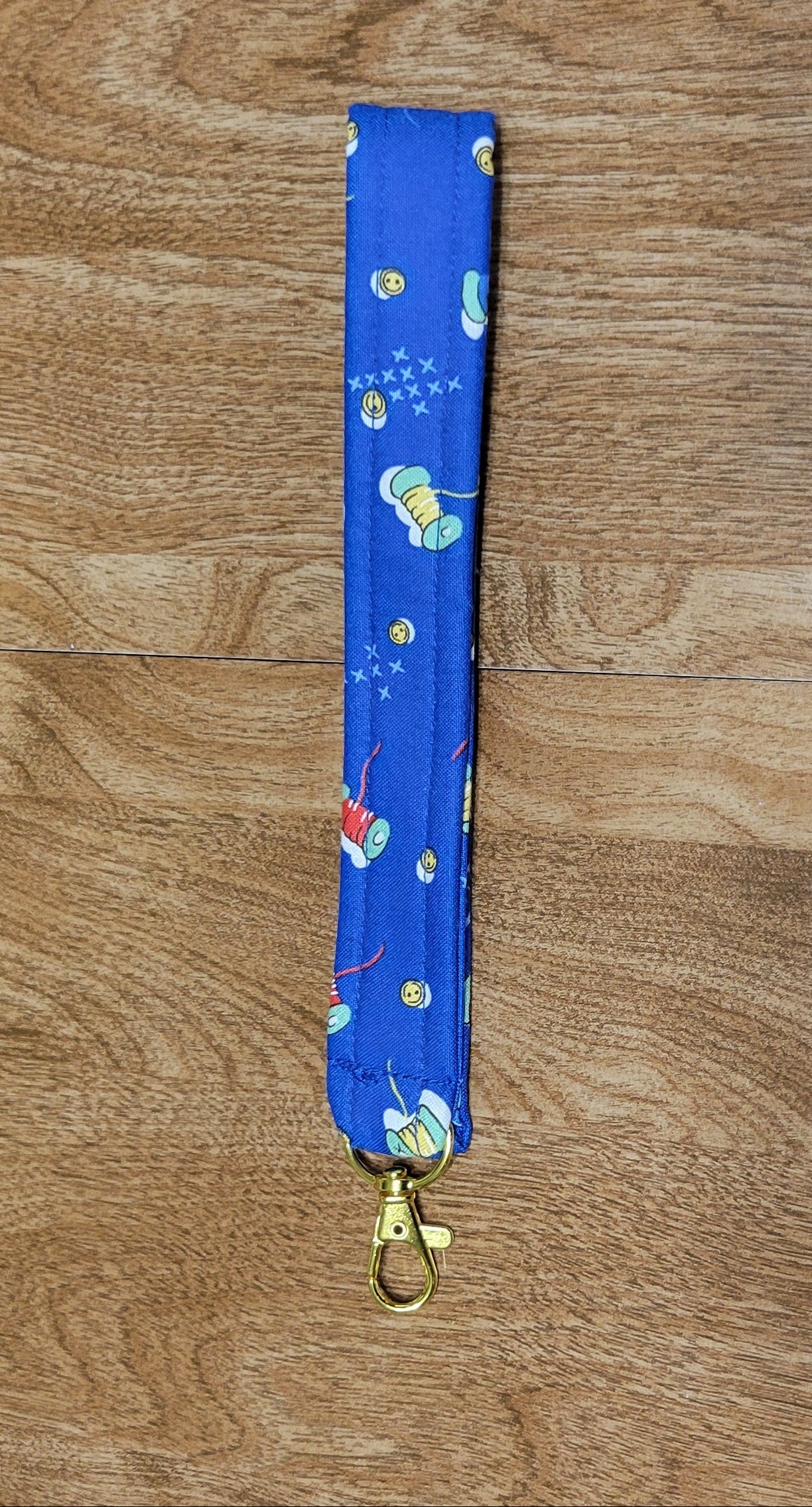 Blue lanyard with spools of string design on a wooden surface
