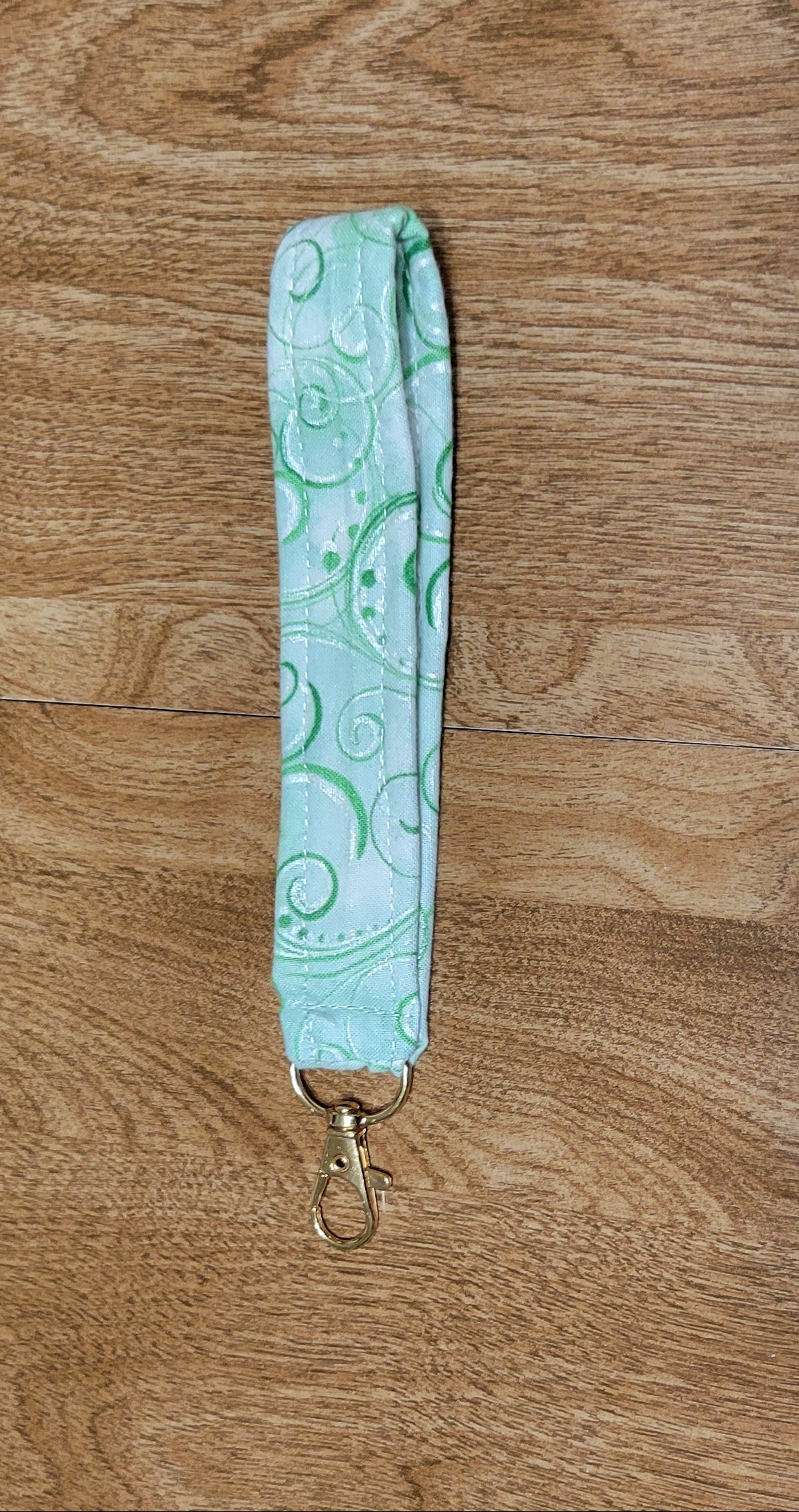 Light blue strap with gold clasp on a wooden surface