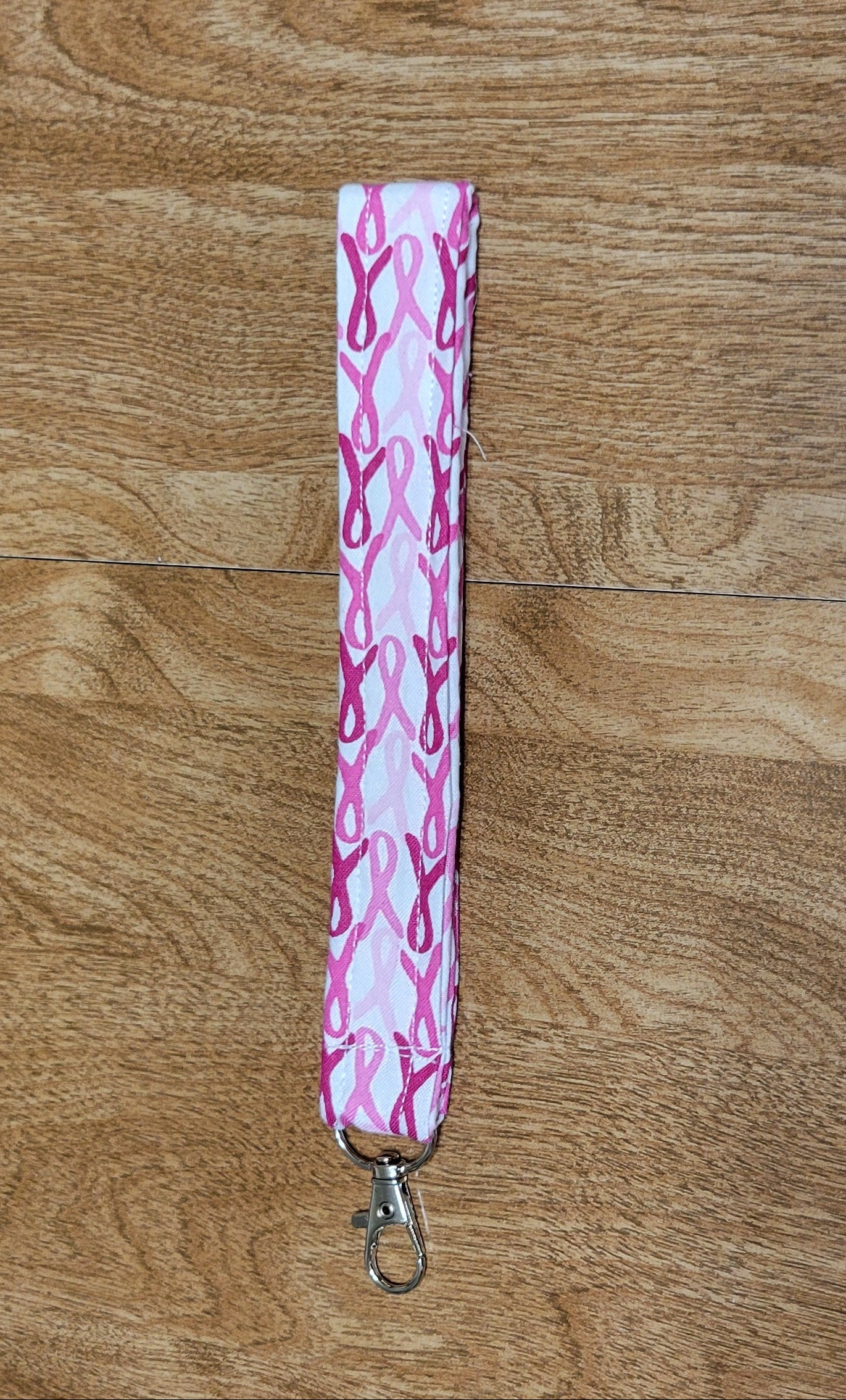 Pink and white patterned lanyard on a wooden surface