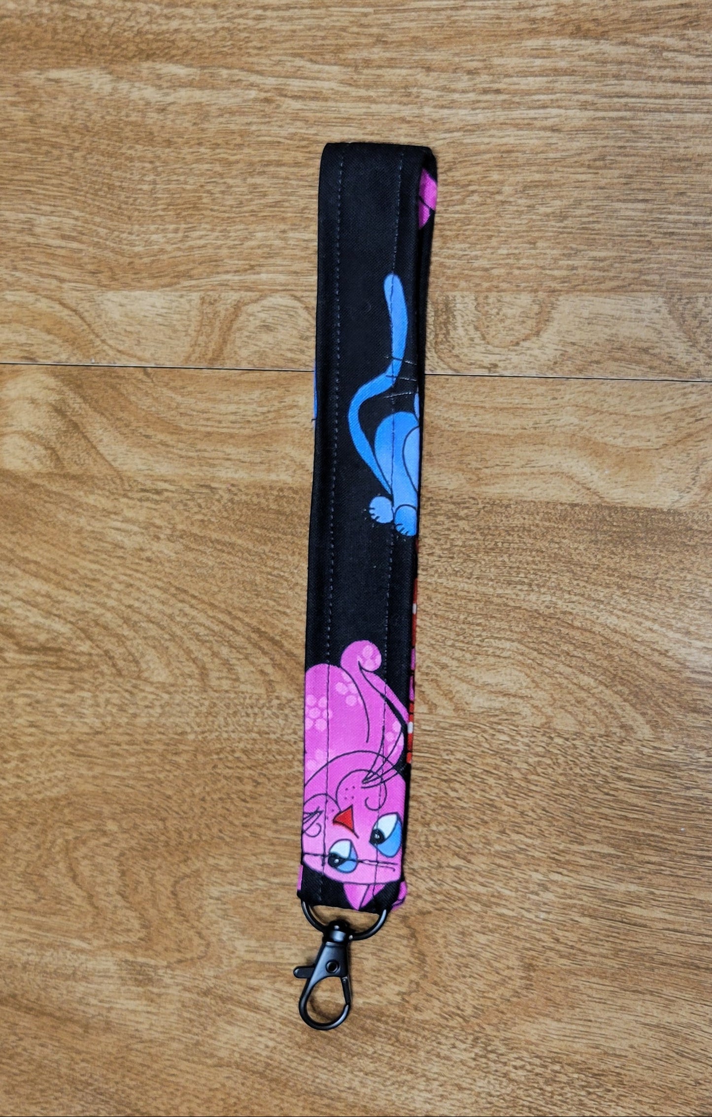 Black strap with colorful cat design on a wooden surface