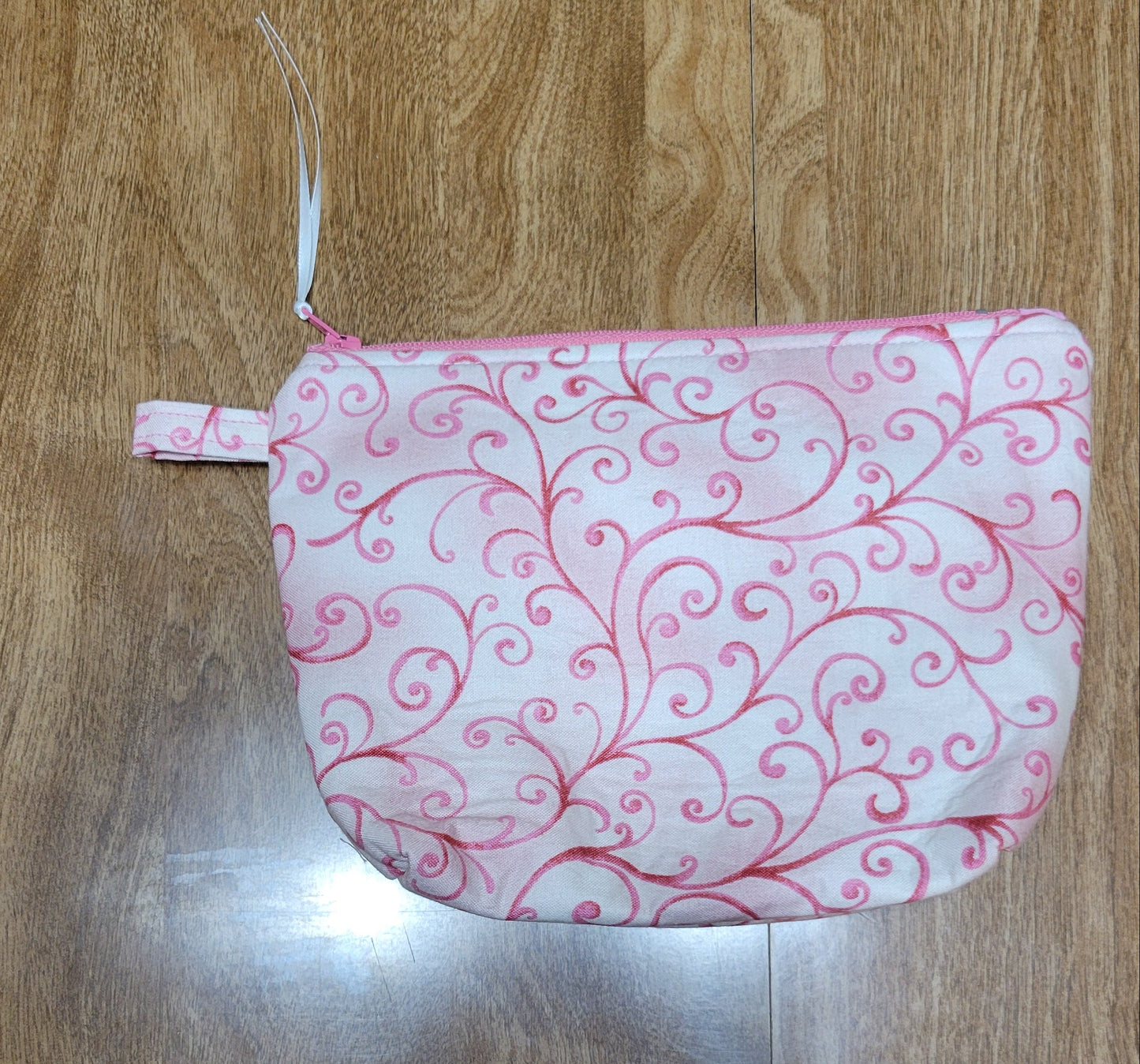 Pink-patterned make-up bag on a wooden surface