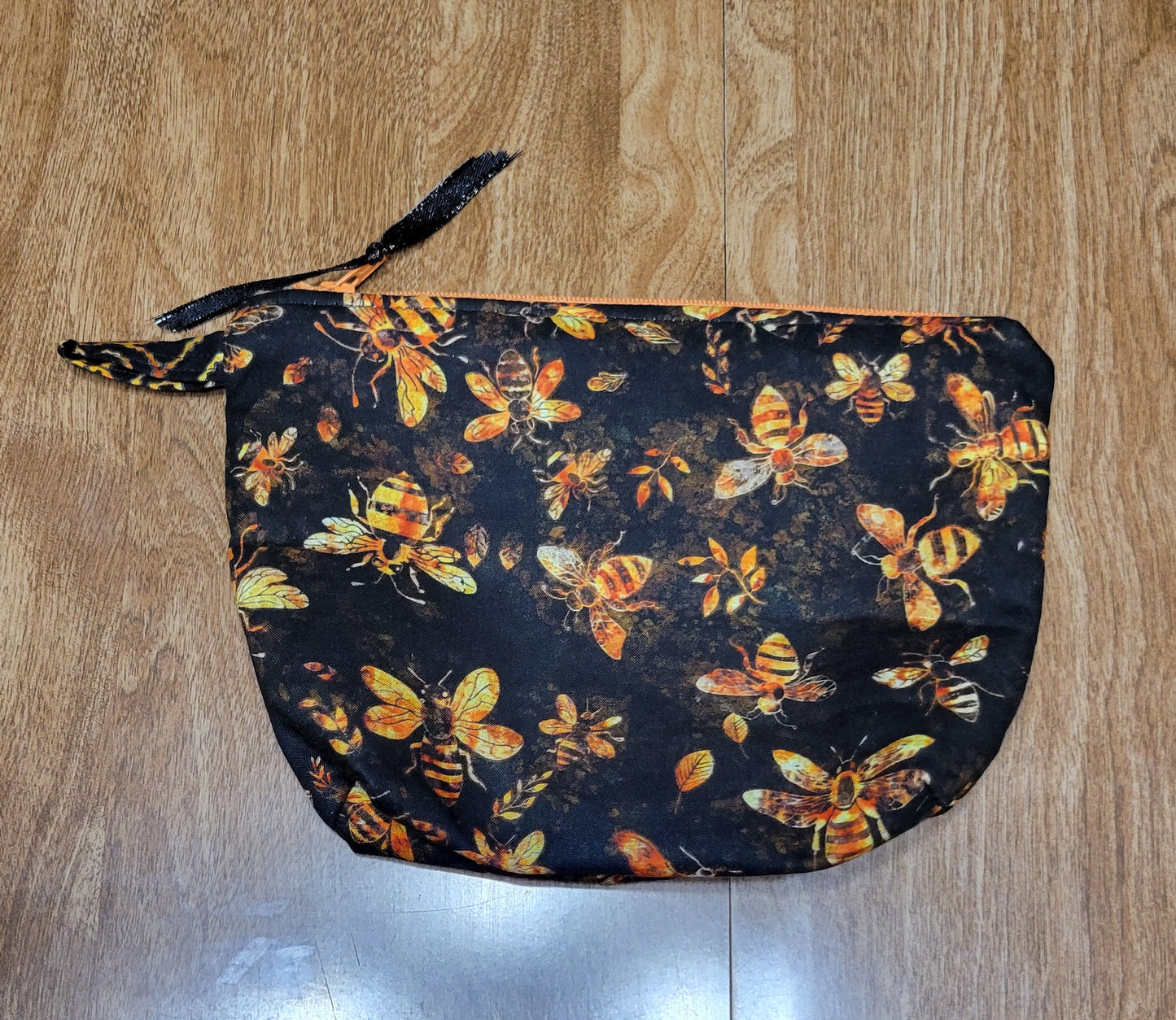 Black make-up bag with gold bees and a orange liner. 