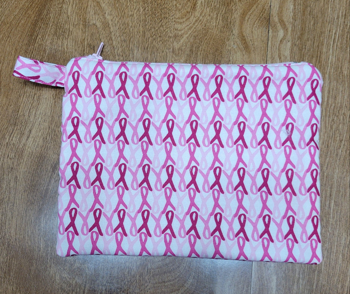 White fabric with pink ribbon pattern on a wooden surface