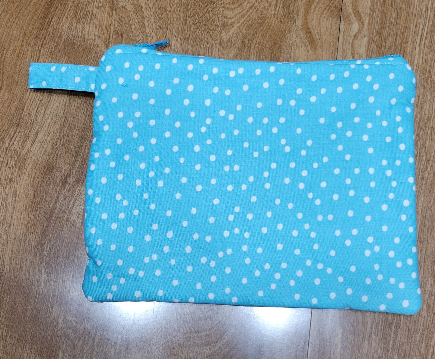 Turquoise fabric with white polka dots on a wooden surface