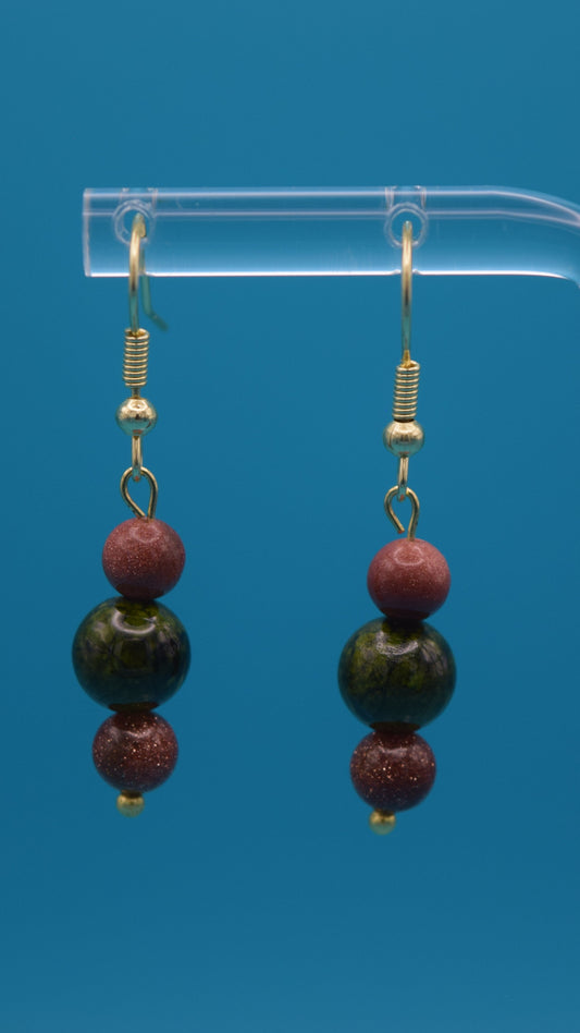 Bronze with gold sparkle on the top and bottom. With a mid-size bead in the center colored with a metallic green bead. Accented with gold. Hanging 3/4 of an inch below the ear.
